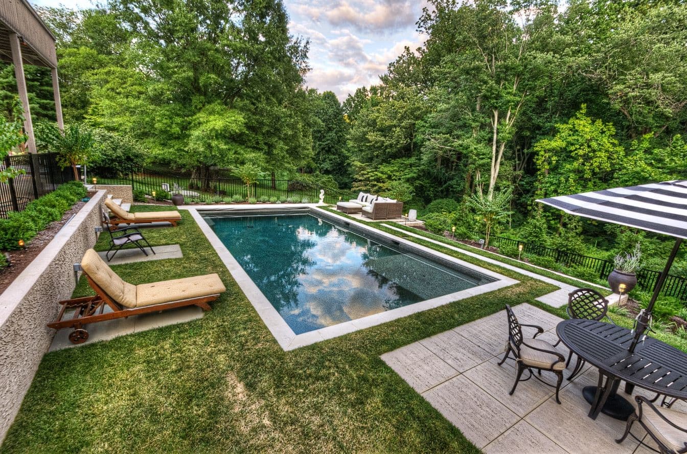 Modern rectangular pool set into a wooded Wilmington-area backyard by Field of Dreams