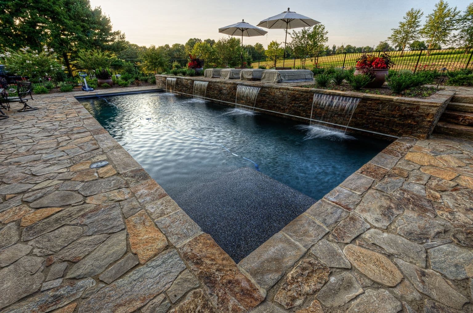 Custom luxury backyard pool and stone deck by Field of Dreams