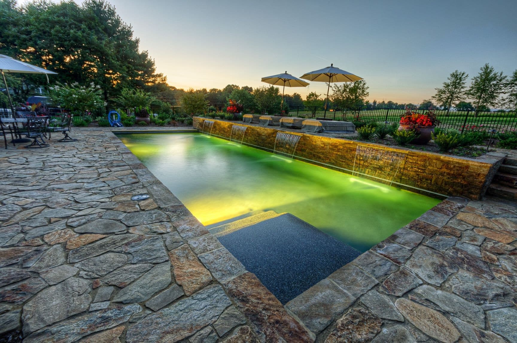 Custom luxury backyard pool and stone deck by Field of Dreams