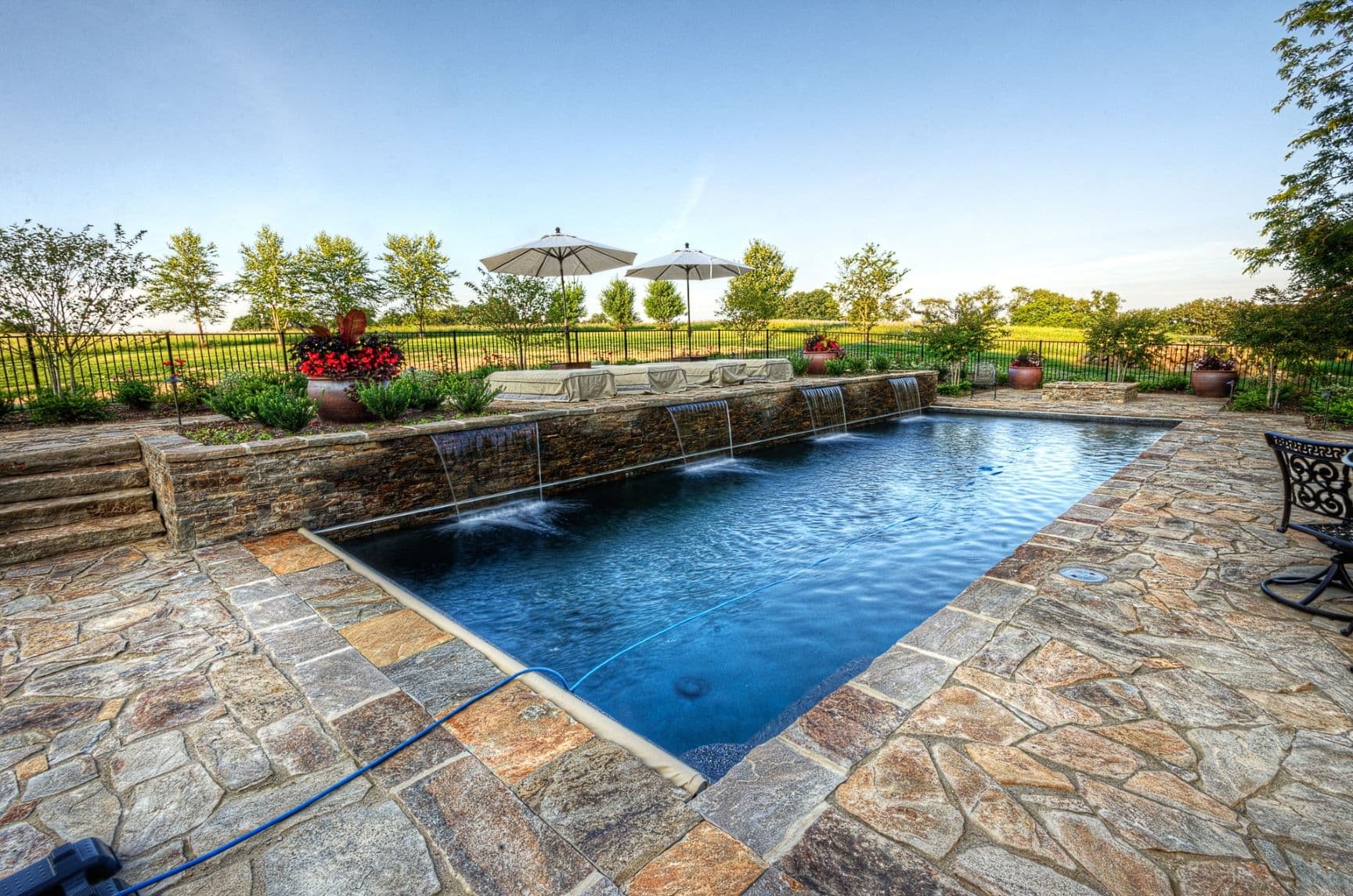 Custom luxury backyard pool and stone deck by Field of Dreams