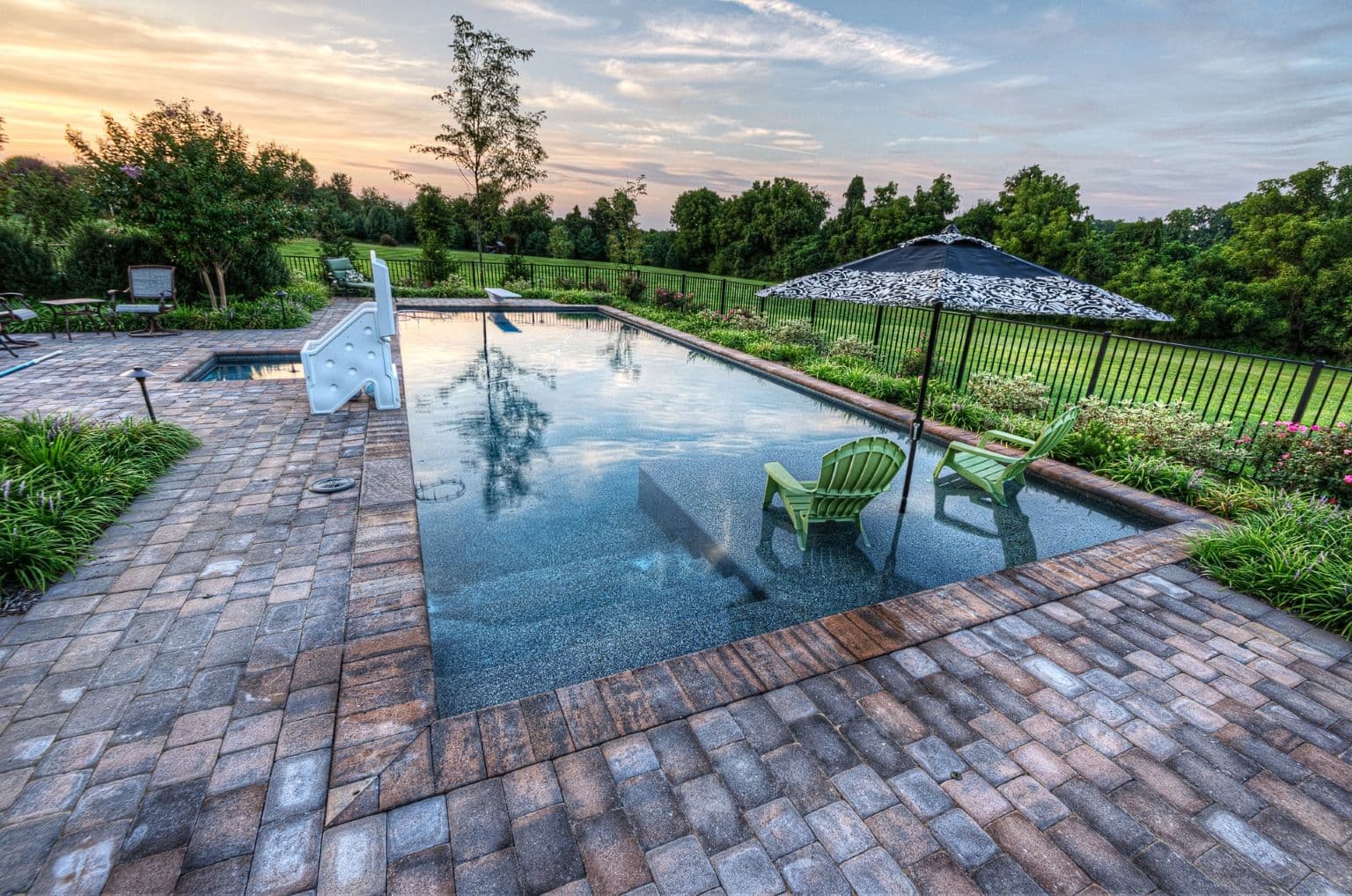 Paver deck and rectangular pool at dusk